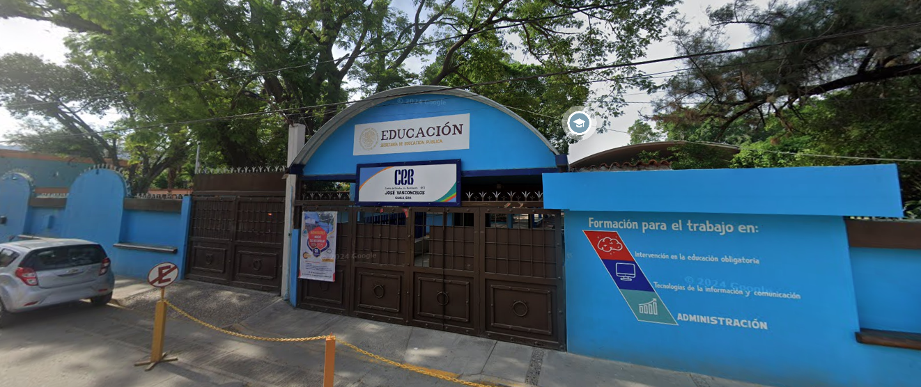 Fotografía en la que se muestra la entrada del plantel, conformada por dos portones de color café. Arriba de uno de los portones hay un cartel que dice Ce E Be. A la izquierda y a la derecha de los portones hay muros de color azul que rodean el plantel.